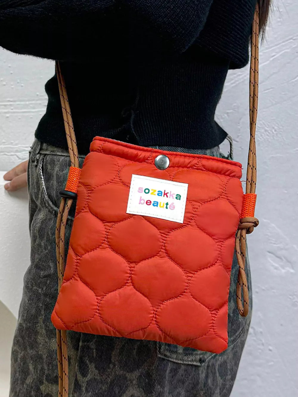 Vibrant quilted mini crossbody bag in red with adjustable strap and logo patch.