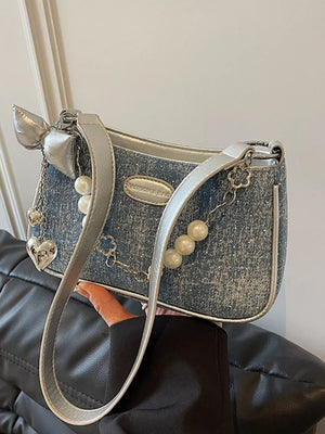 Denim shoulder bag with pearl chain, silver bow, heart and clover charms.
