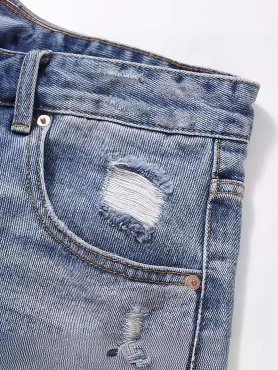Ripped denim bermuda shorts in medium wash with distressed details and frayed edges.