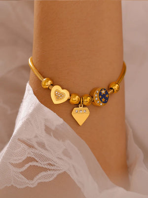 Gold celestial charm bracelet with diamond heart, diamond, and moon charms.