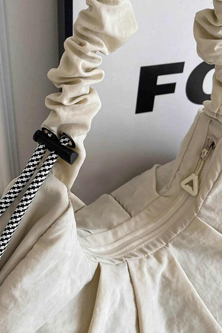 Gathered crescent shoulder bag in beige with ruched strap and black and white rope detail