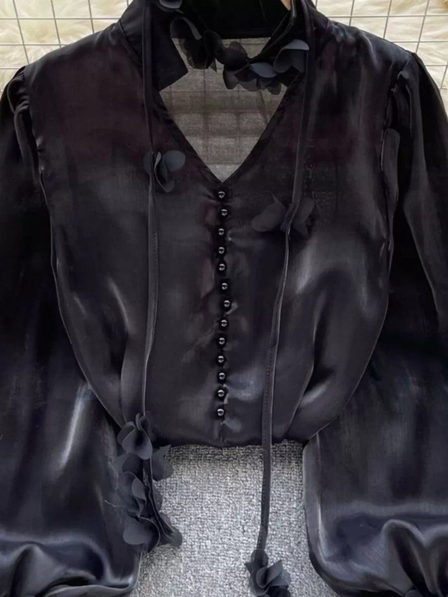 Black button-down shirt with delicate floral appliqué and tie neck detail.