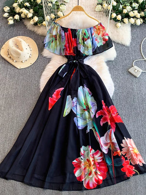 Botanical off-shoulder A-line dress with colorful floral print on black fabric and a belted waist.
