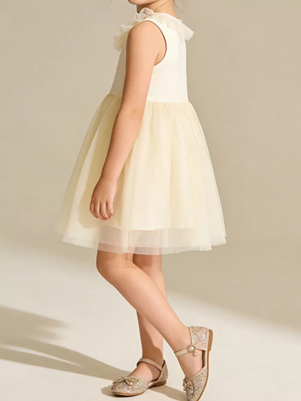 Cream tulle dress with ruffled collar and layered skirt, sleeveless.