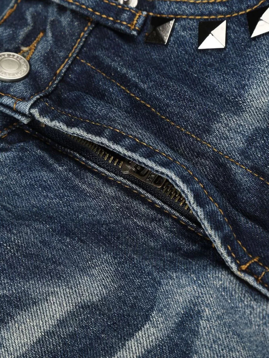 Blue distressed bootcut jeans with studded accents and zipper detail.