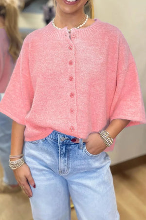 Pink acrylic boxy knit cardigan with button front and short sleeves.