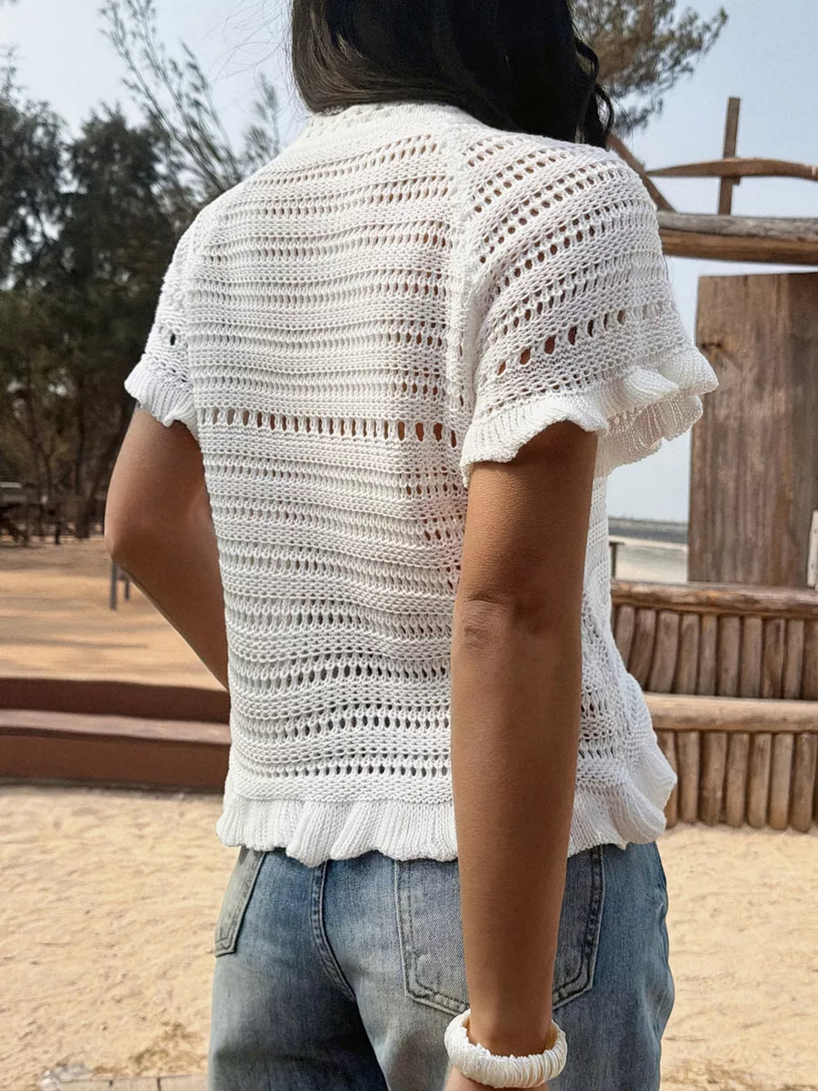 White knit top with openwork pattern, ruffled hem, and short sleeves.