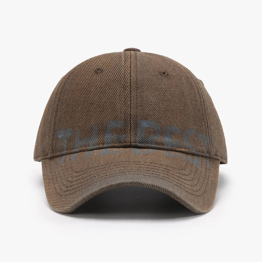 Textured denim baseball cap in Coffee Brown with faded blue graphic text.