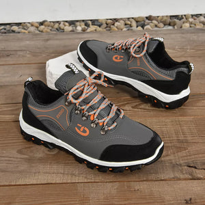 Grey low-top sneakers with patterned orange and grey laces and orange accents.