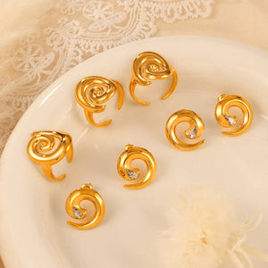 Gold swirl stud earrings with zirconia accents and matching rings.