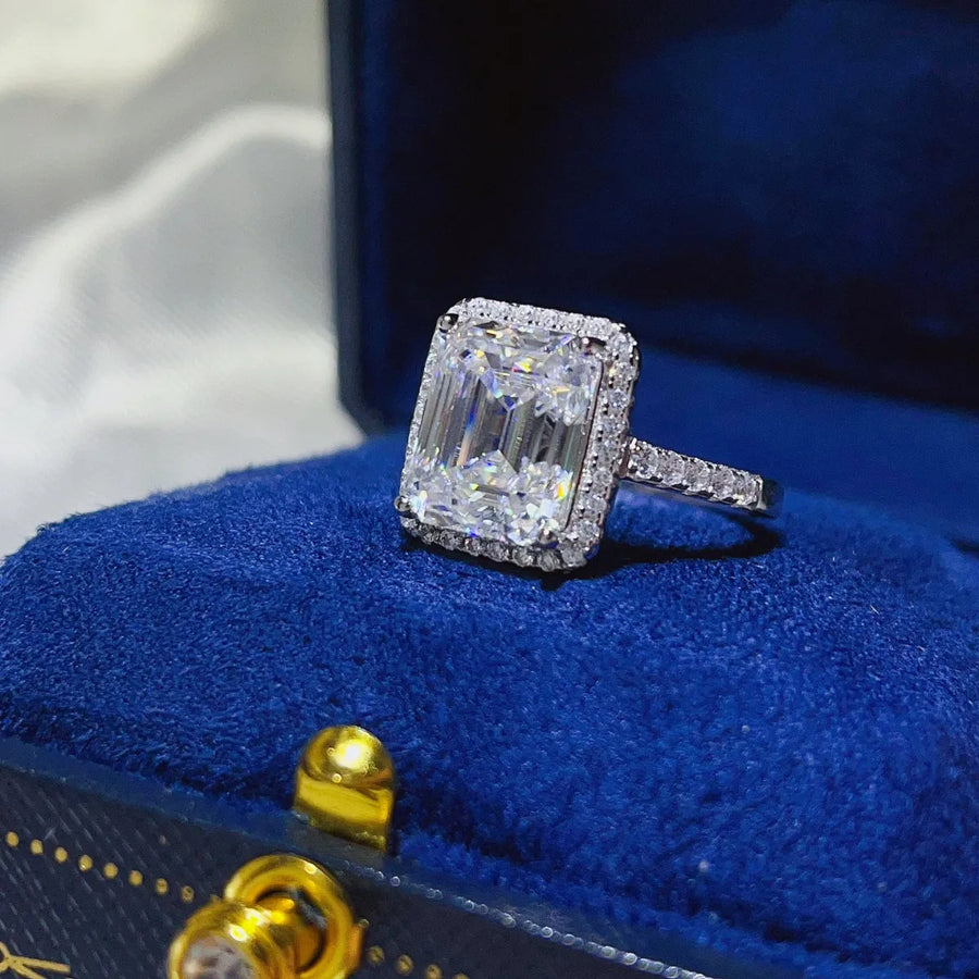 Emerald cut moissanite halo ring in sterling silver with pavé band.
