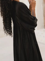 Black tie-neck midi dress with puff sleeves and a flowing skirt.