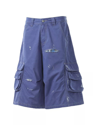 Blue distressed maternity cargo capris with pocket details and plaid patches.