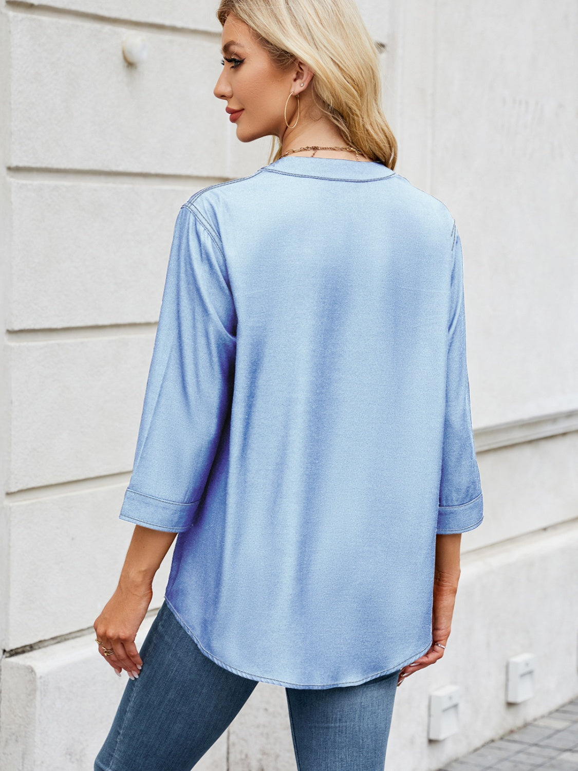 Light blue denim henley blouse with 3/4 sleeves and curved hem.