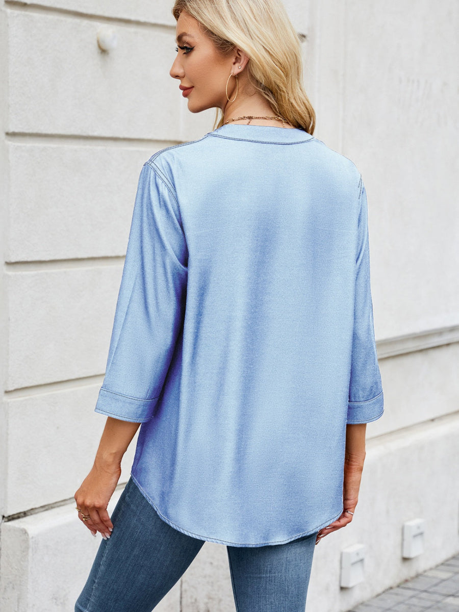 Light blue denim henley blouse with 3/4 sleeves and curved hem.