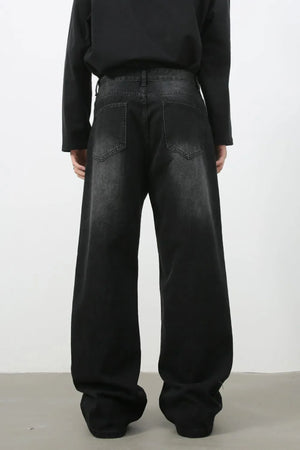 Faded black denim palazzo jeans with a wide leg and cat's whisker detail.