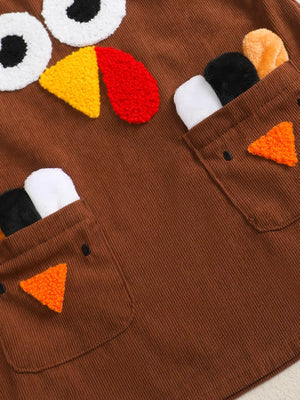 Brown corduroy baby dress with turkey applique, eyes, beak, and feather details.