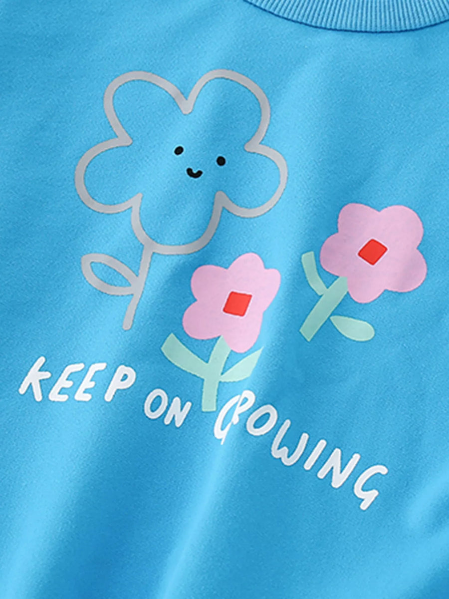 Baby sweatshirt in sky blue with floral print and "KEEP ON GROWING" text.