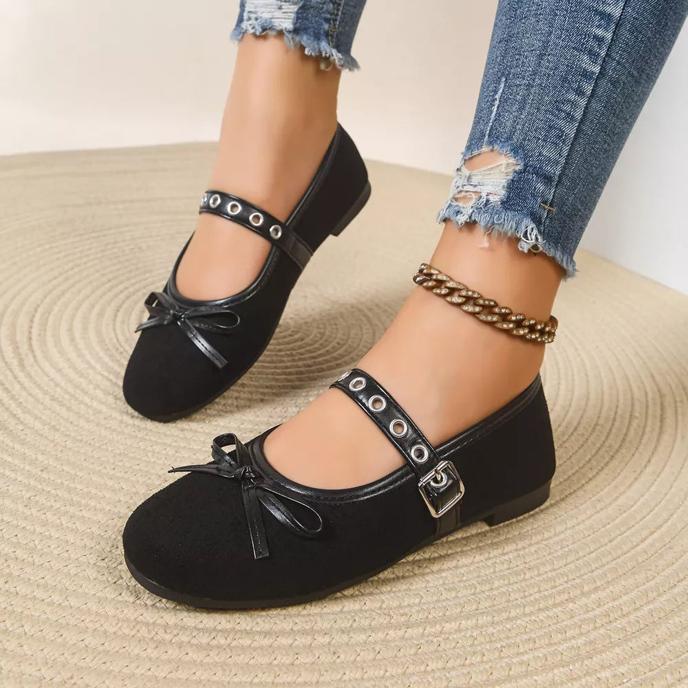 Black Mary Jane flats with bow detail and adjustable strap with eyelets and buckle.