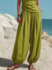 Green one-shoulder top and wide-leg pants set with pockets, styled casually.