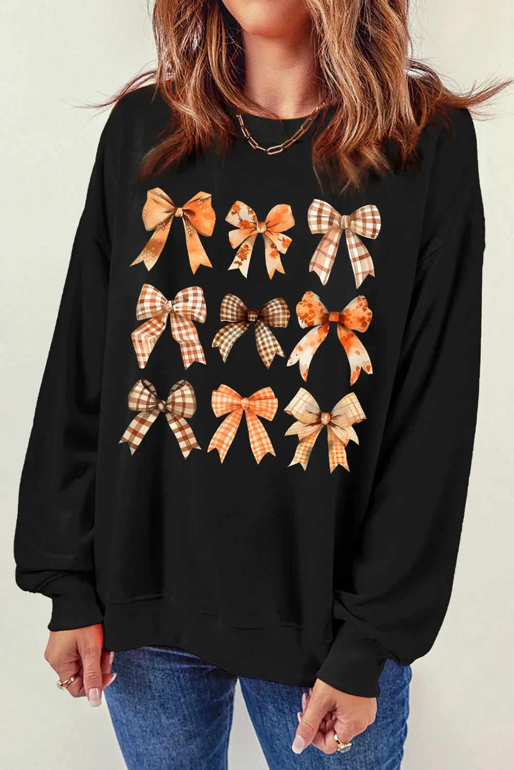 Black crewneck sweatshirt with a grid of autumn-themed bow prints.
