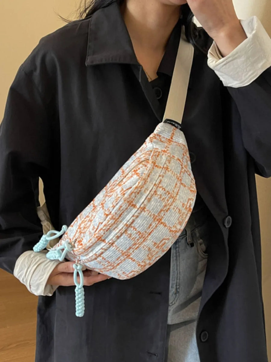 Textured tweed belt bag in orange and light blue plaid with braided pulls and a cream strap.