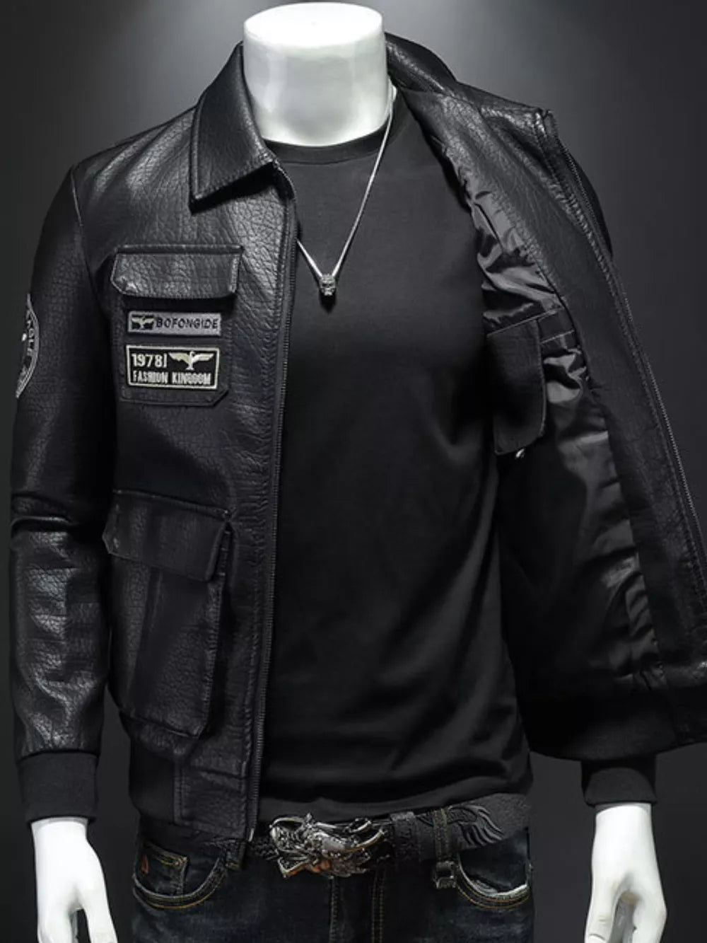 Black leather bomber jacket with patches and chest pockets, open front showing black shirt and necklace.