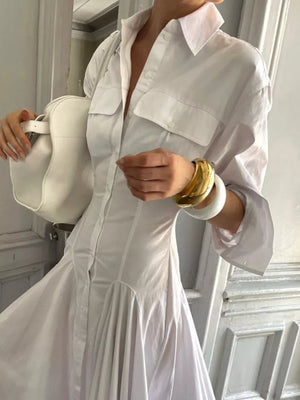 White shirt dress with button front, chest pockets, and flared skirt.