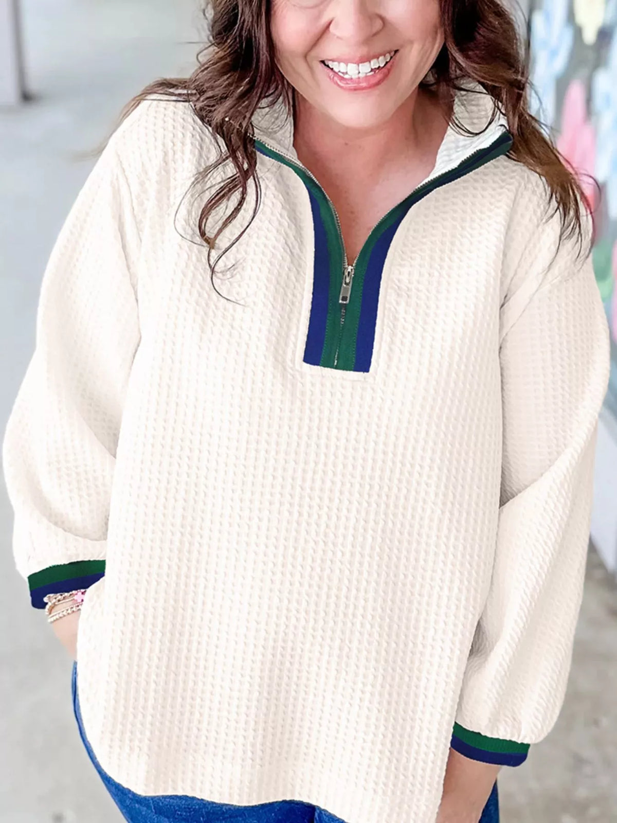 White textured half-zip sweatshirt with blue and green striped collar and cuffs