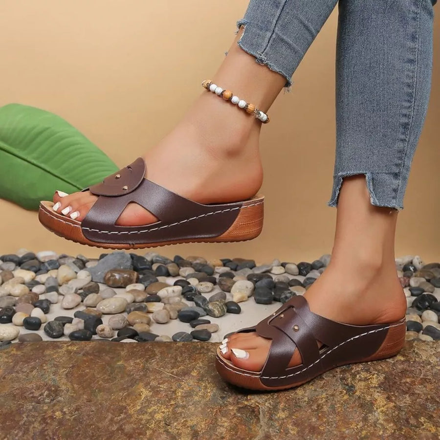 Brown slip-on wedge sandals with riveted detail and cut-out straps.