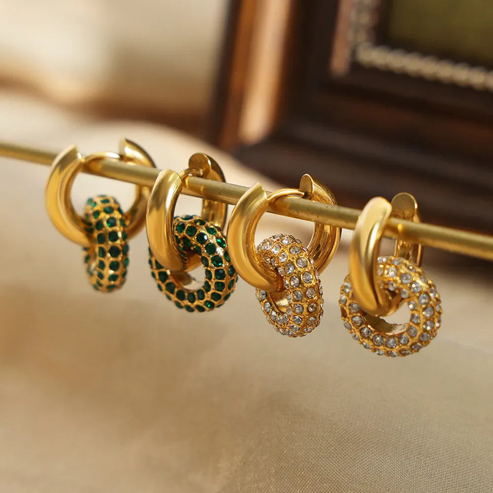 Gold hoop earrings with interlocking circles, some with dark green stones and others with clear pavé stones.