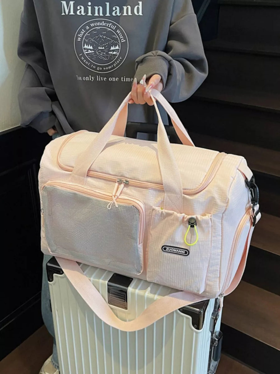 Pink duffel bag with mesh pocket and adjustable strap, styled with a grey sweatshirt.