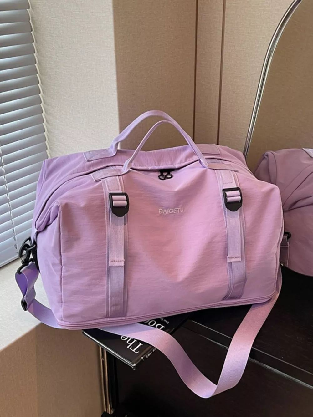 Purple nylon travel bag with buckle straps and adjustable shoulder strap