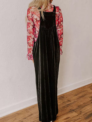 Black velvet wide-leg romper with adjustable straps and a V-neck bodice, worn over a floral print top.
