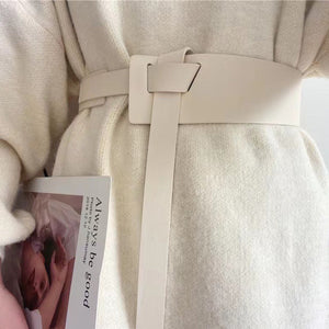 Ivory wide belt with knotted buckle and long tail, cinching a cream sweater.