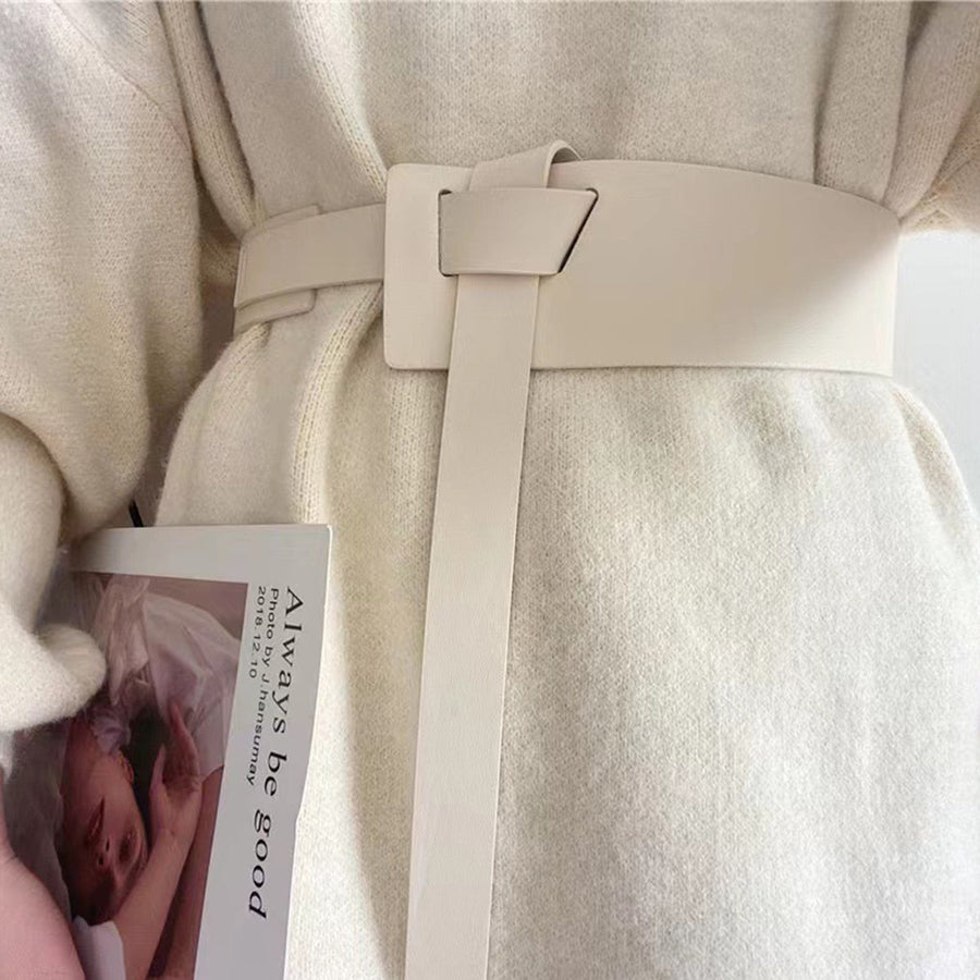 Ivory wide belt with knotted buckle and long tail, cinching a cream sweater.