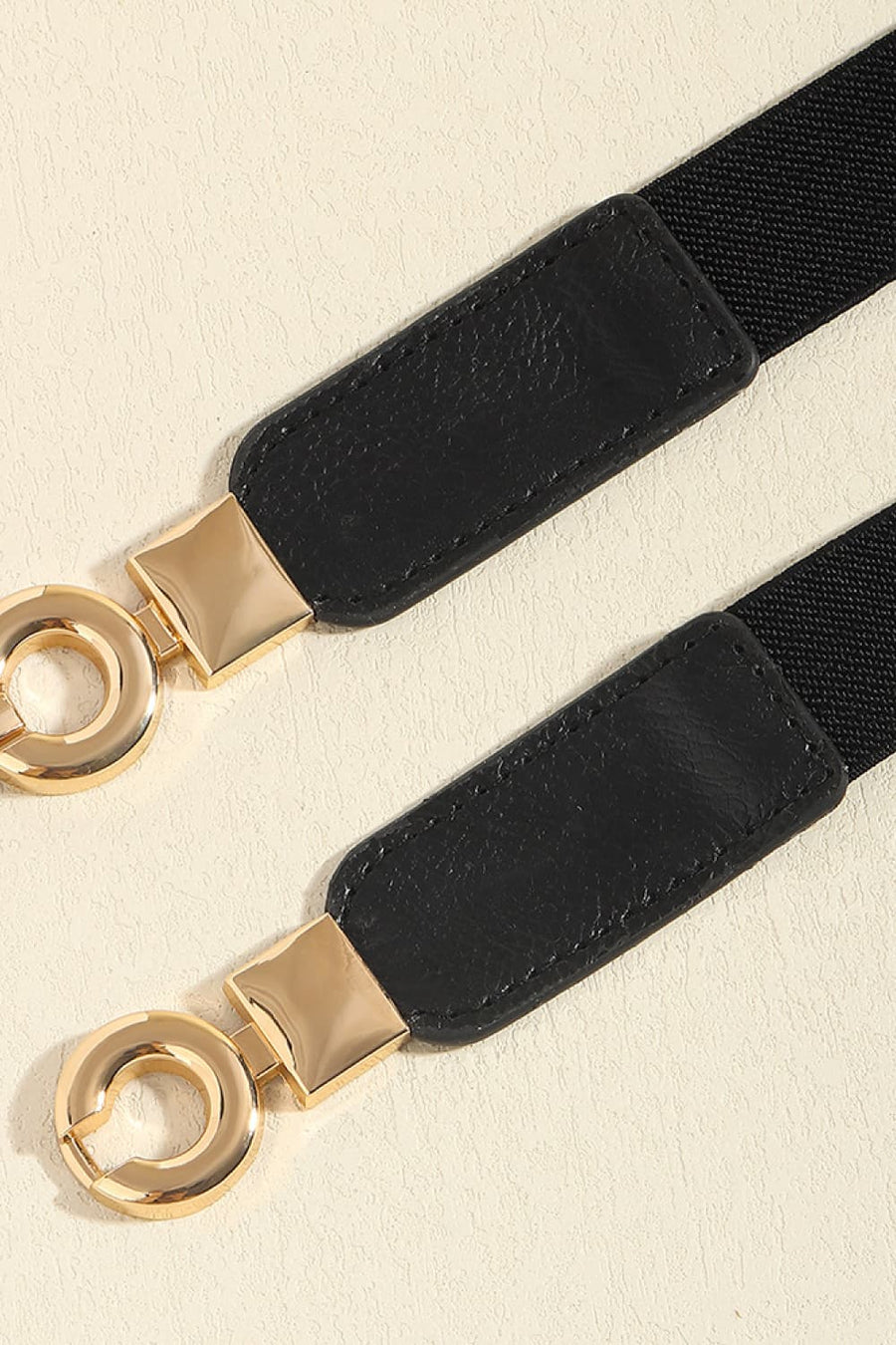 Black elastic belt with faux leather tabs and gold hardware detail