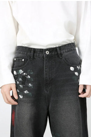 Dark wide-leg jeans with painterly white and green brushstrokes and distressed details.