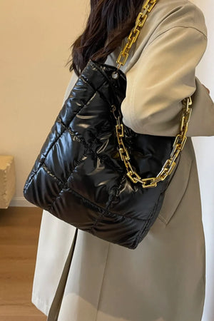 Black quilted nylon tote bag with shiny finish and gold chain handle.