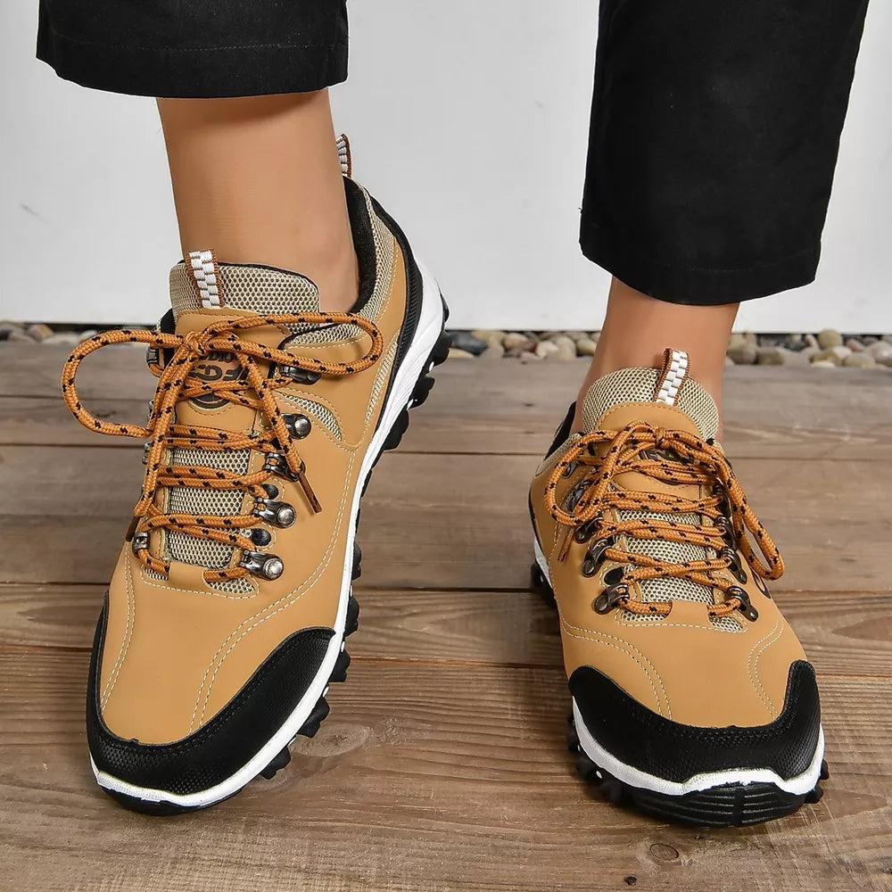 Brown lace-up low-top sneakers with patterned orange laces and black toe caps.