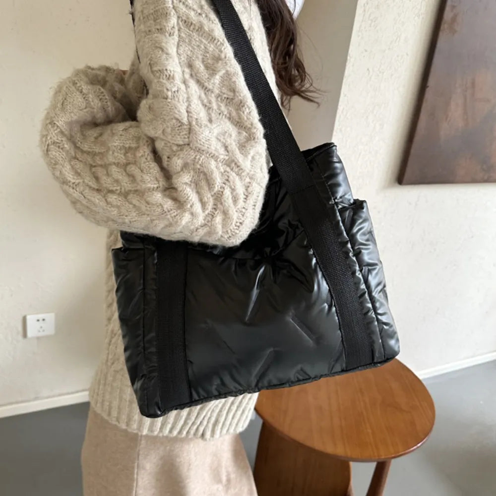 Black padded nylon tote bag with exterior pockets and black strap.