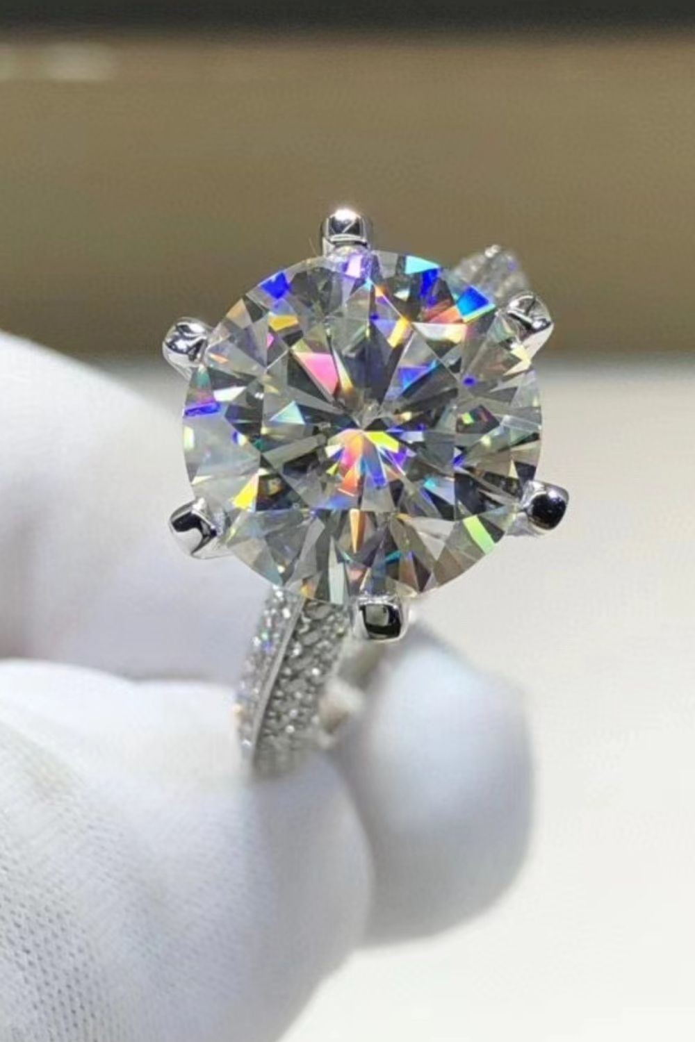 Silver pavé band moissanite solitaire ring with a round brilliant cut center stone.