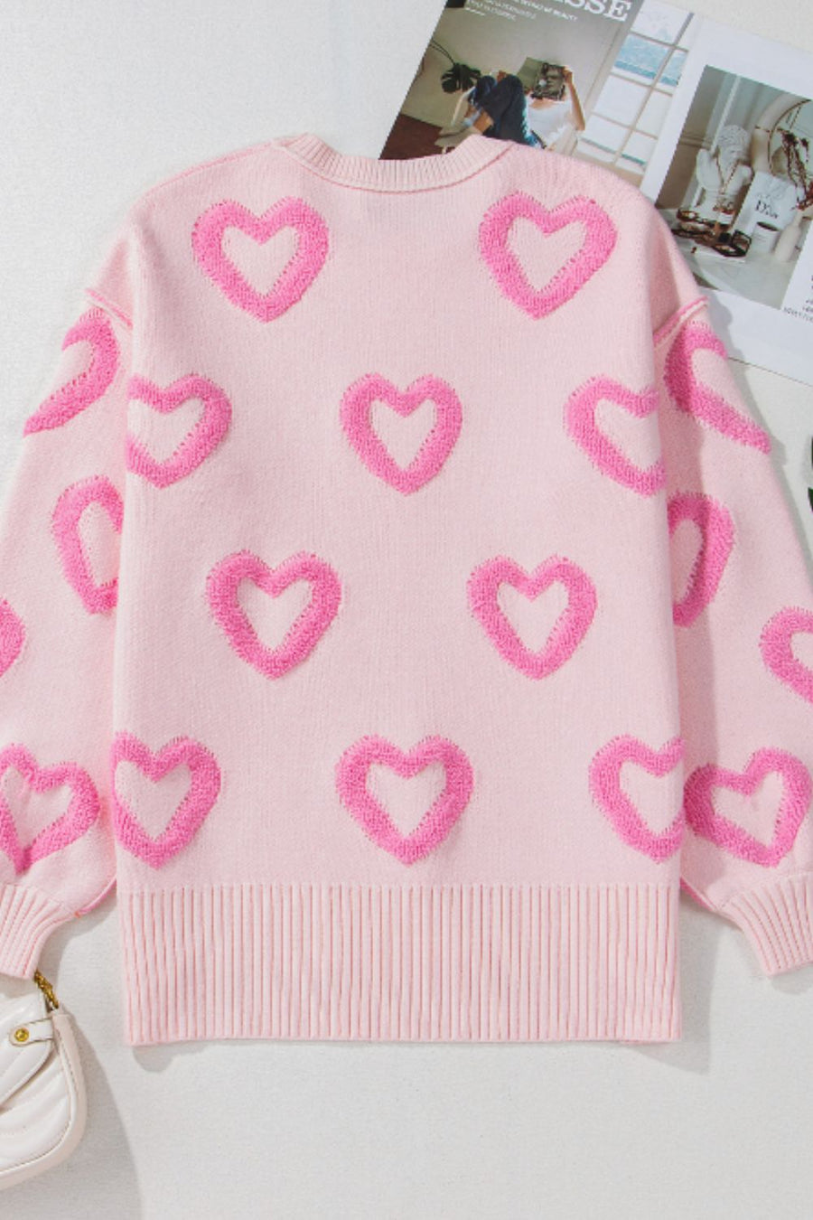 Pink knit sweater with allover textured heart appliques and balloon sleeves.
