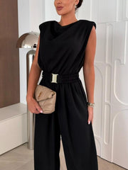 Black cowl neck wide-leg jumpsuit with gold buckle belt and padded shoulders.