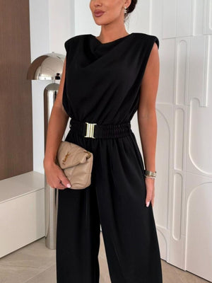 Black cowl neck wide-leg jumpsuit with gold buckle belt and padded shoulders.