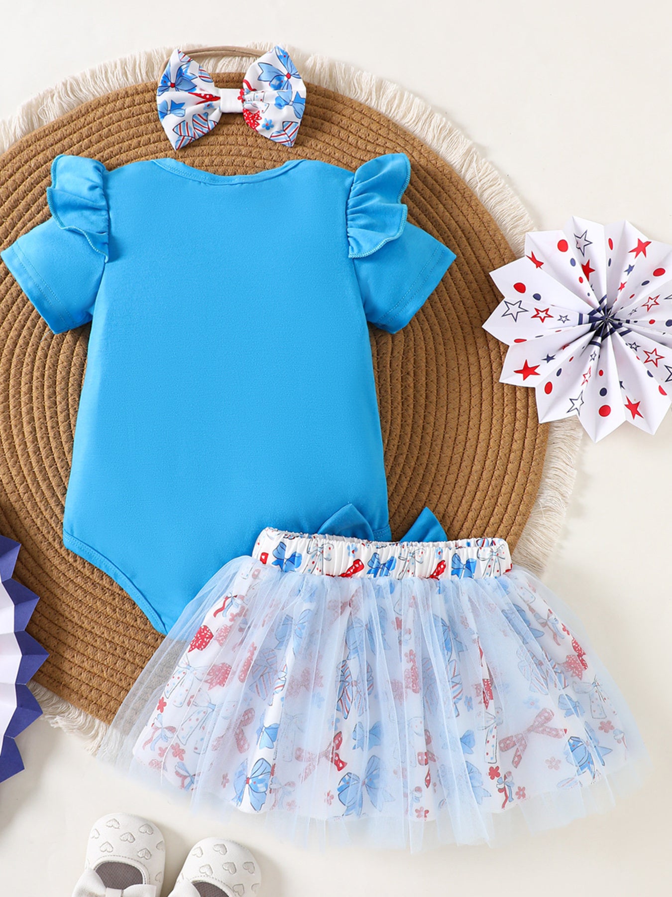 Blue cotton baby outfit with ruffled sleeves, patterned skirt, and matching bow headband.