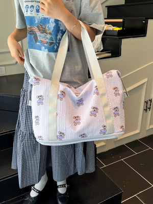 Tote bag with teddy bear pattern, white with light purple bears, textured fabric, white straps.