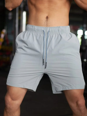 Gray athletic shorts with drawstring and pockets, shown on a man.