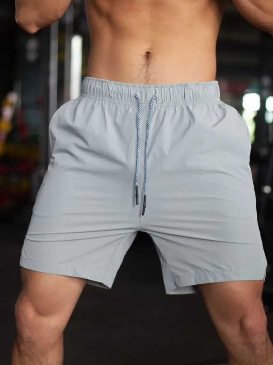 Gray athletic shorts with drawstring and pockets, shown on a man.