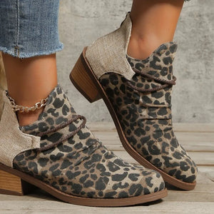Leopard print ankle boots with cutout sides and a gold chain accent.